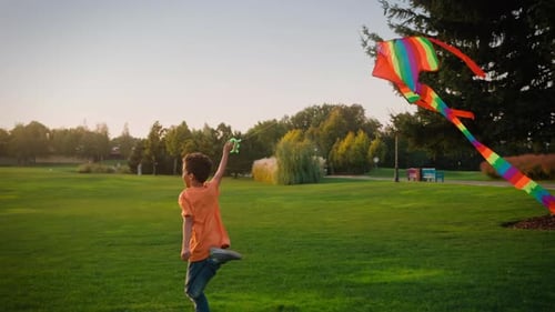 Energetic Boy Happily Chasing with Colorful Kite Outdoor