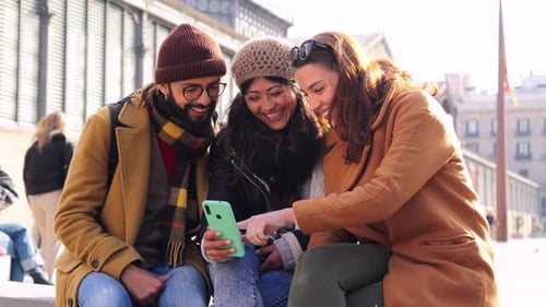 Group of Young Happy People Using a Smartphone Device Outdoors Three Cheerful Friends Smiling and