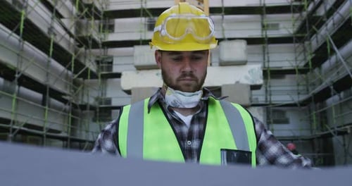 A young man going over building plans at a construction site