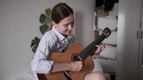 Young Woman Playing Guitar in a Bedroom