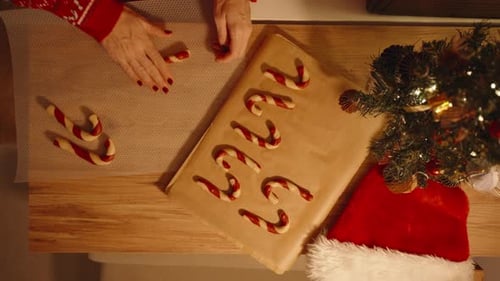 Woman Pressing Dough on Bubble Wrap Sheet While Finished Cookies Rest on Parchment in Overhead View
