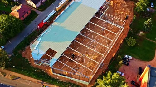 Large Steel Frame Building Under Construction in Residential Neighborhood at Sunset viewed from