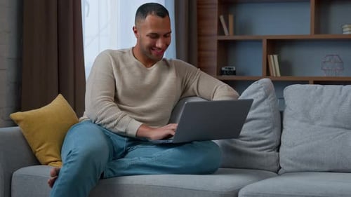 Man Using Laptop on Couch in Home