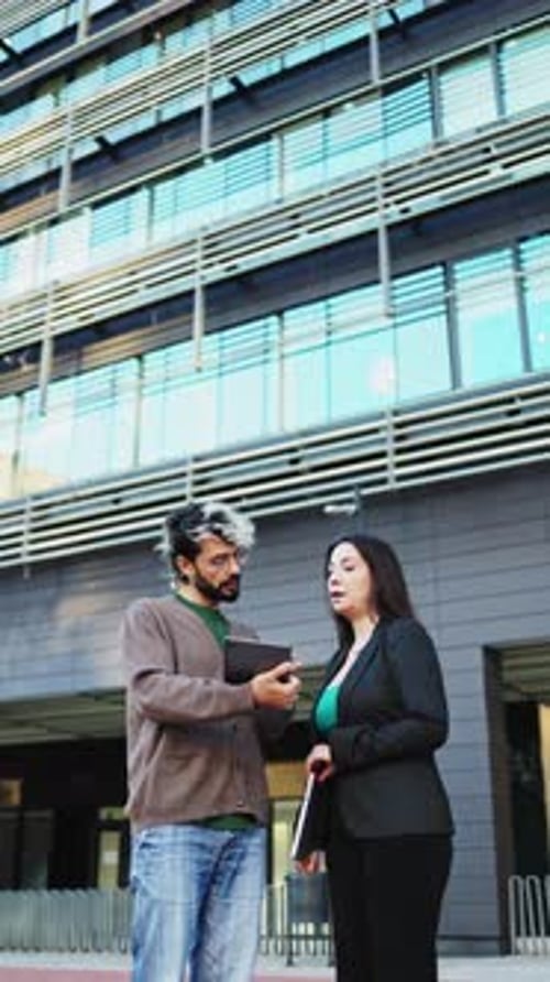 Two business people having a discussion while using a digital tablet outside the office