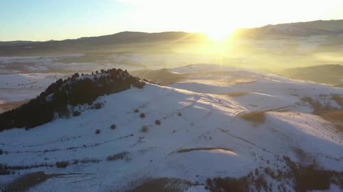 Aerial view of sunset over misty winter mountains