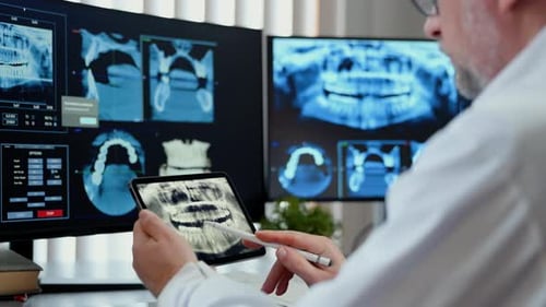 Doctor Dentist Reviewing Dental Xray Images on Multiple Screens and Tablet Modern Dental Diagnostics