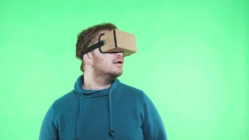 Shocked man experiencing virtual reality in wearable tech glasses on green screen
