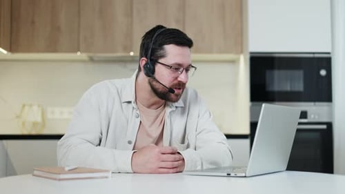 Man with Headset Communicating on Laptop at Home
