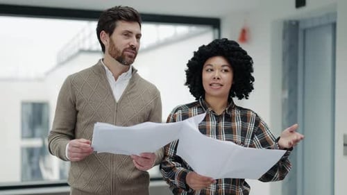 Business Colleagues Collaborate on Blueprints in a Modern Office
