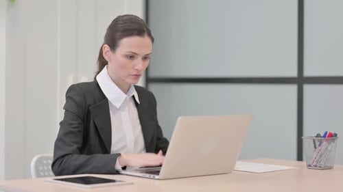 Businesswoman Typing on Laptop in Office