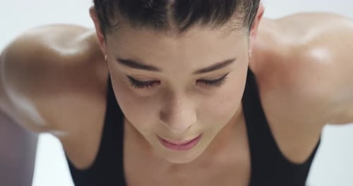 A young woman doing pushups against a grey studio background