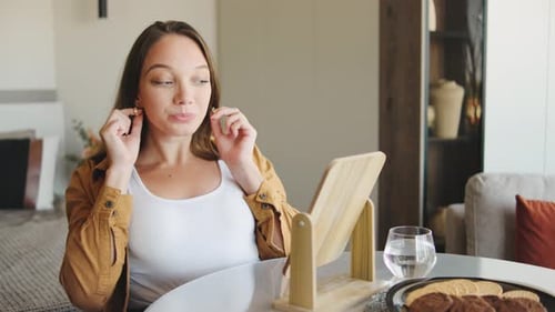 Young Woman Puts On Earrings in her Apartment
