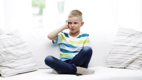 Blond Boy Talking on Phone Sitting on Sofa