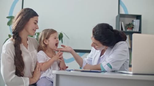 Doctor Examining Little Girl with Mother in Office