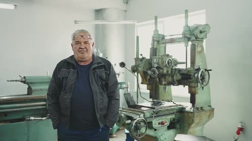 Portrait of an elderly retired pensioneer enjoying his work, locksmith turner in a lathe workshop