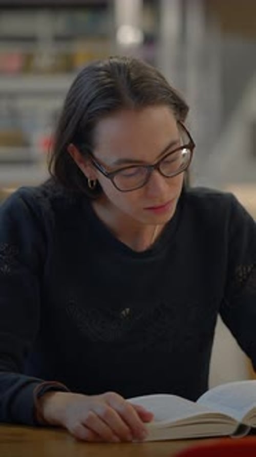 A Focused Woman Deeply Engaged in Reading a Book in the Calming and Quiet Setting of a Library