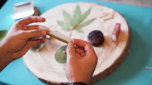 Hands Rolling a Cigarette on Wooden Table