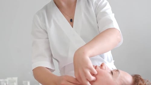 Massagetherapeut massiert Frau Gesicht und Körper