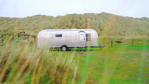 Trailer parked on a green meadow. Camper. Caravan. Motor home. Recreational vehicle. RV.