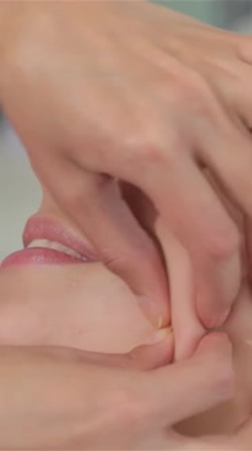 Expert Masseur Rejuvenates Client's Face with a Soothing Massage From Chin to Ear