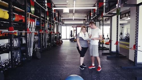 Fitness Trainer with Tablet in Gym Talking to New Client