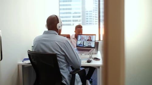 Businessman Video Conferencing at Laptop in Open Plan Office 2529 Years