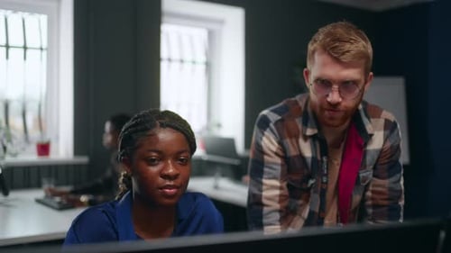 Black Woman and Caucasian Man Working Together on Project in Office Group of Programmers