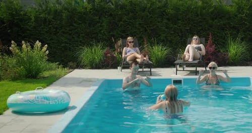 A Friendly Family is Relaxing By the Pool Playing Ball Having a Good Time Together on a Hot Summer