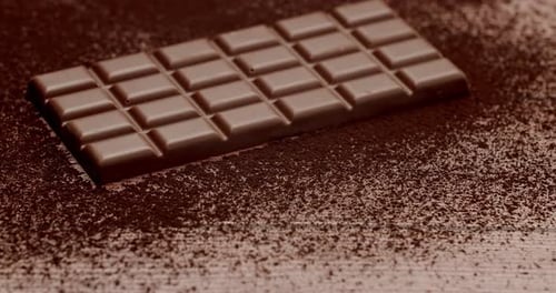 Delicious Milk Chocolate Bar on Cocoa Powder Background in CloseUp