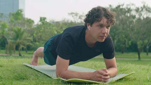 Mann macht Planke während des morgendlichen Trainings im Park