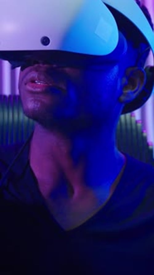 Man Using VR Headset and Controllers in Dark Room