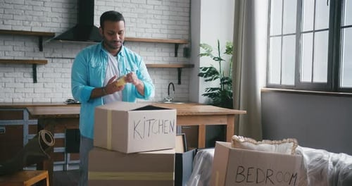 Man Taping Boxes in New Apartment