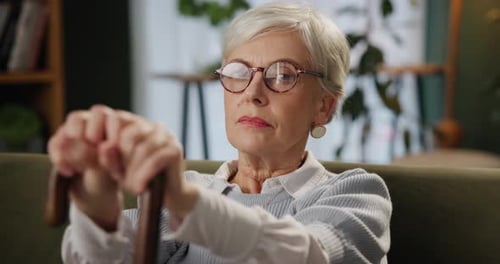 Senior Woman Sitting on Couch Holding Cane