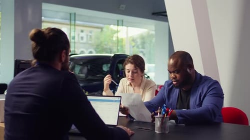 Customers in Dealership Completing Necessary Car Payment Paperwork