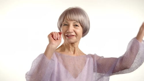 Mulher sênior dançando com alegria em suéter roxo