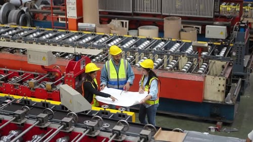 Workers partners holding blueprint discussing at manufacturing factory.