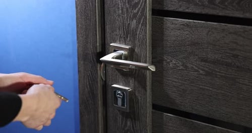Woman closing wooden door with key indoors, closeup