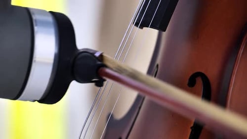 Bow Moving Across Cello Strings Creating Classical Music Sound