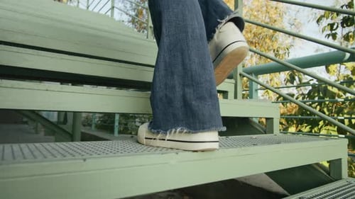 Young Woman Wearing Blue Jeans and White Sneakers Up the Stairs Back View Female Walking in the City