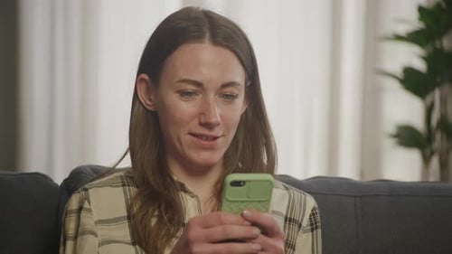 Woman Using Cell Phone on Couch at Home