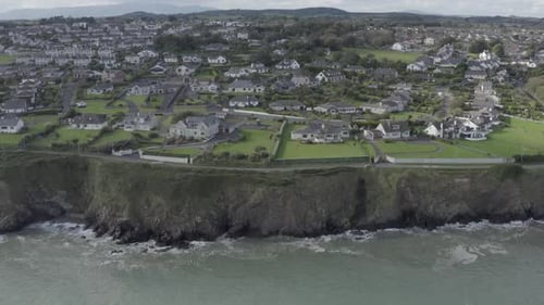 Aerial flight: Rocky seaside cliff estates of Tramore, south Ireland
