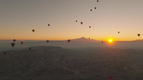 Drone view of hundreds of colorful hot air balloons soaring at sunrise in Cappadocia