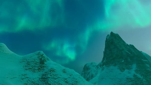 Aurores boréales au-dessus des montagnes enneigées