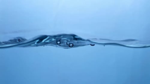 Water Surface Slow Motion Abstract Background. Bubbles rise to the surface. Fresh water waves with s