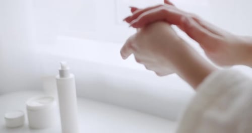 Person Moisturizing Hands with Beauty Products