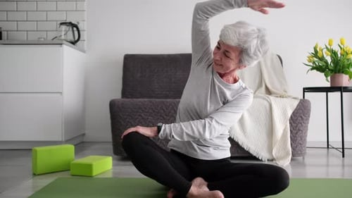 Senior Woman Stretching on Yoga Mat Indoors