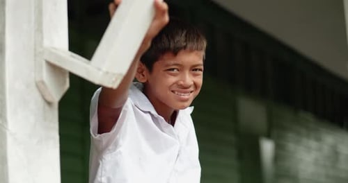 Slow motion scene of a poor Asian elementary school student in white uniform is smiling for greeting