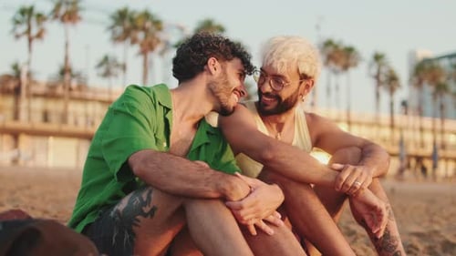 Casal homossexual apaixonado conversando sentado na praia ao nascer do sol