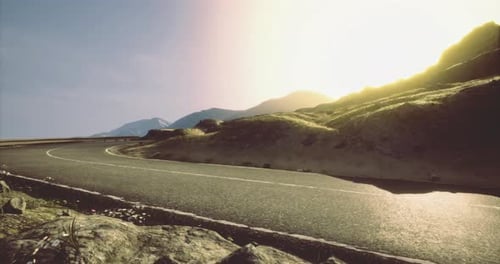 Curved Road Through a Mountain Landscape at Sunset Near a Coastal Area
