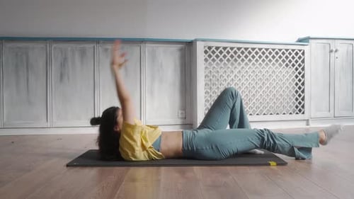 Eine Frau führt in einem Fitnessstudio ein Bauchmuskeltraining auf einer Matte durch.